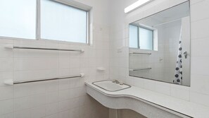 Un bagno con piastrelle bianche, un lavandino, uno specchio e una finestra.