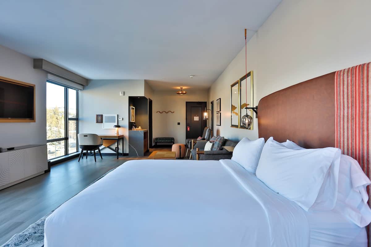 Una habitación de hotel moderna con una cama grande, un escritorio, una silla y un sofá.