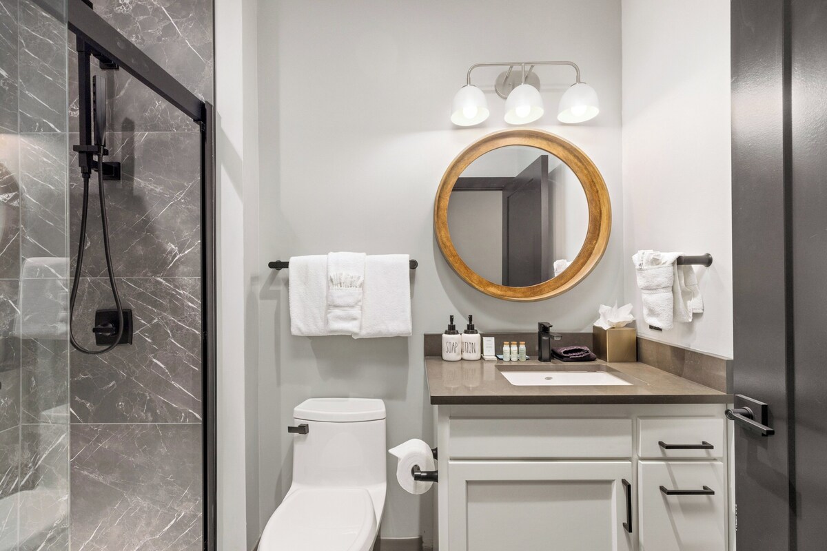 A modern bathroom with a shower, toilet, sink, and vanity.