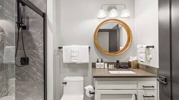 A modern bathroom with a shower, toilet, sink, and vanity.