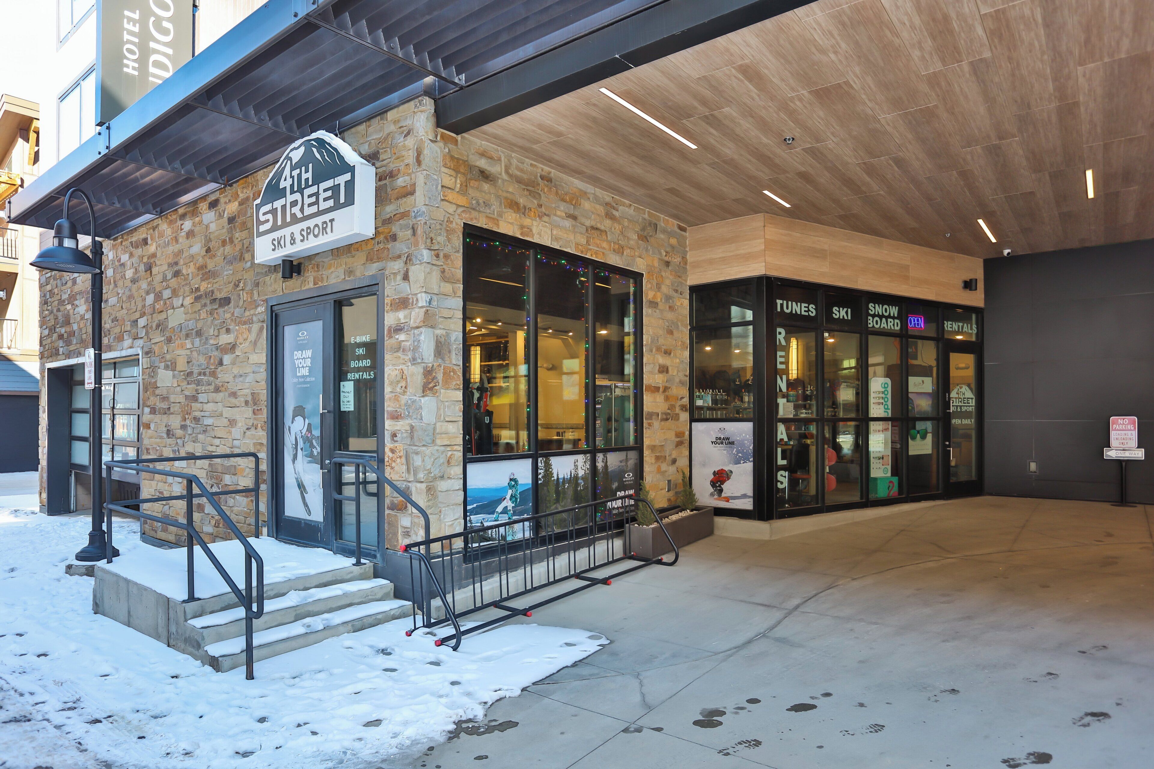 A hotel entrance with a stone facade, glass doors, and a sign indicating ski and sport services.