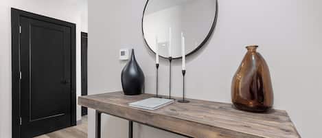 Un intérieur moderne avec une console en bois, un miroir rond, un vase et un livre.