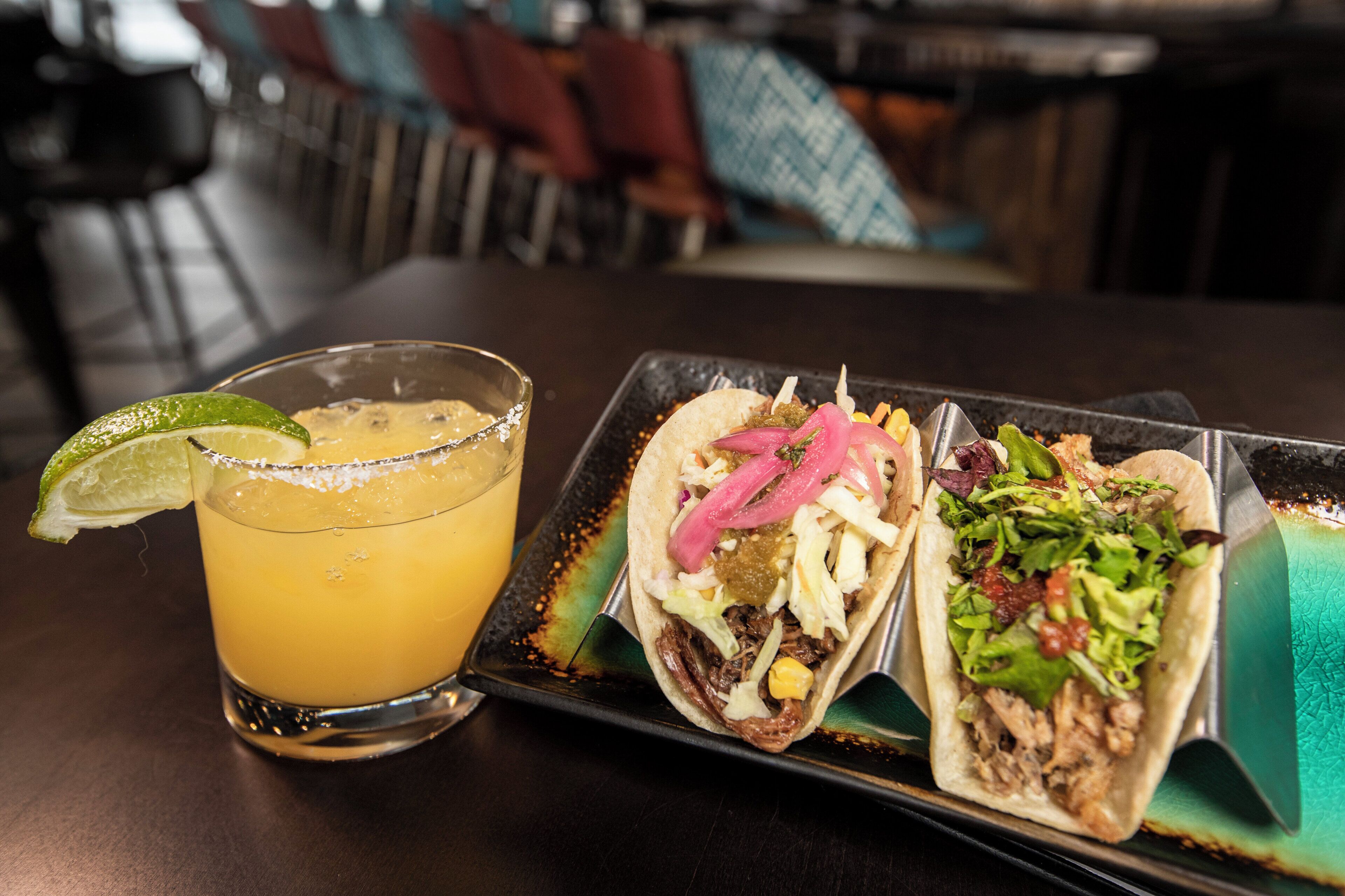 A table with a drink and two tacos.