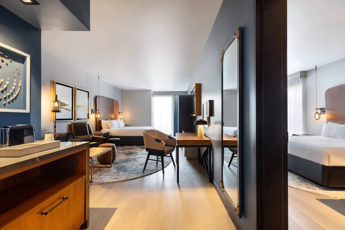 Una habitación de hotel moderna con una cama grande, un escritorio, una silla y un espejo amplio.