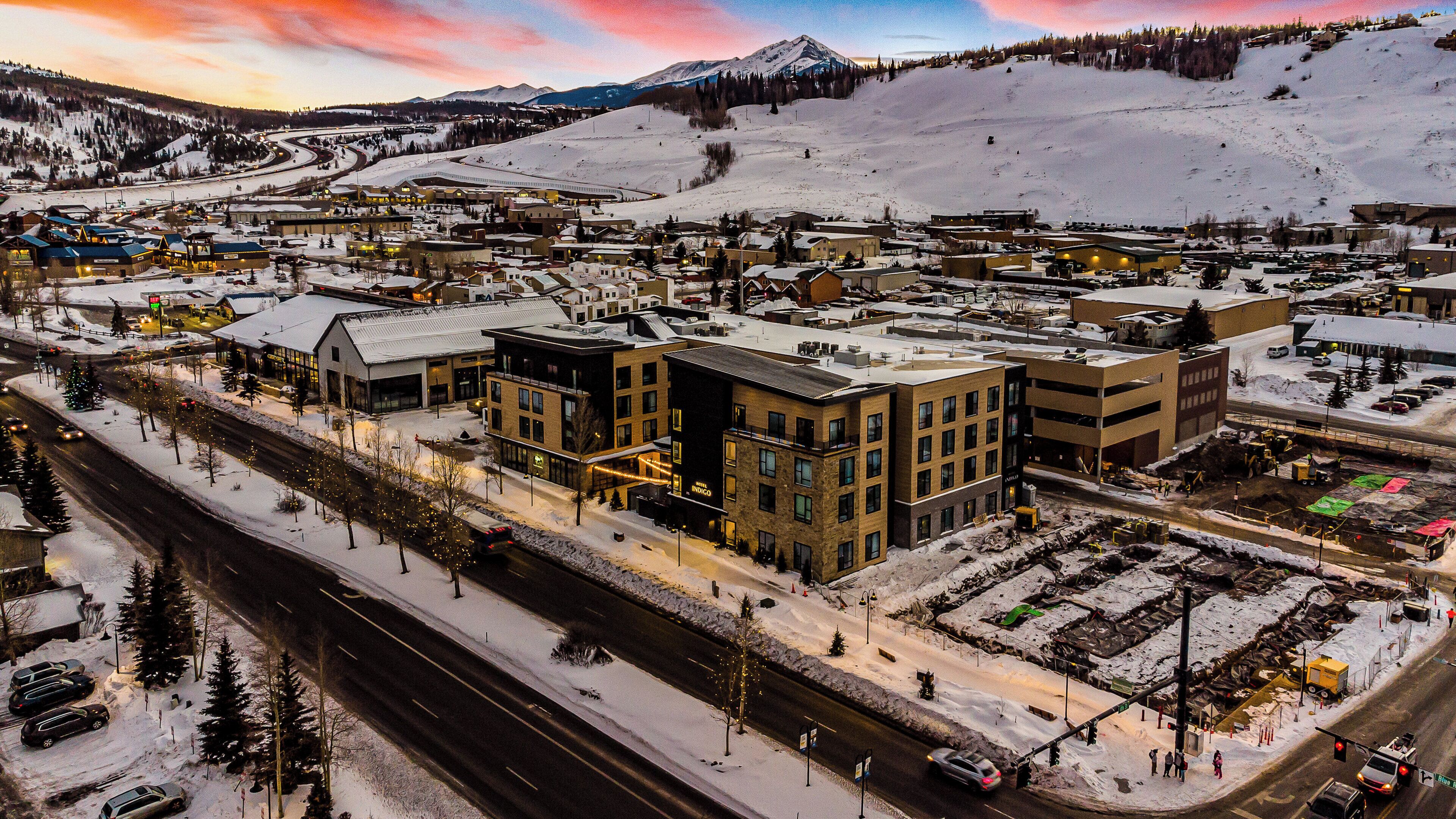A snow-covered town with buildings, roads, and a mountain in the background.