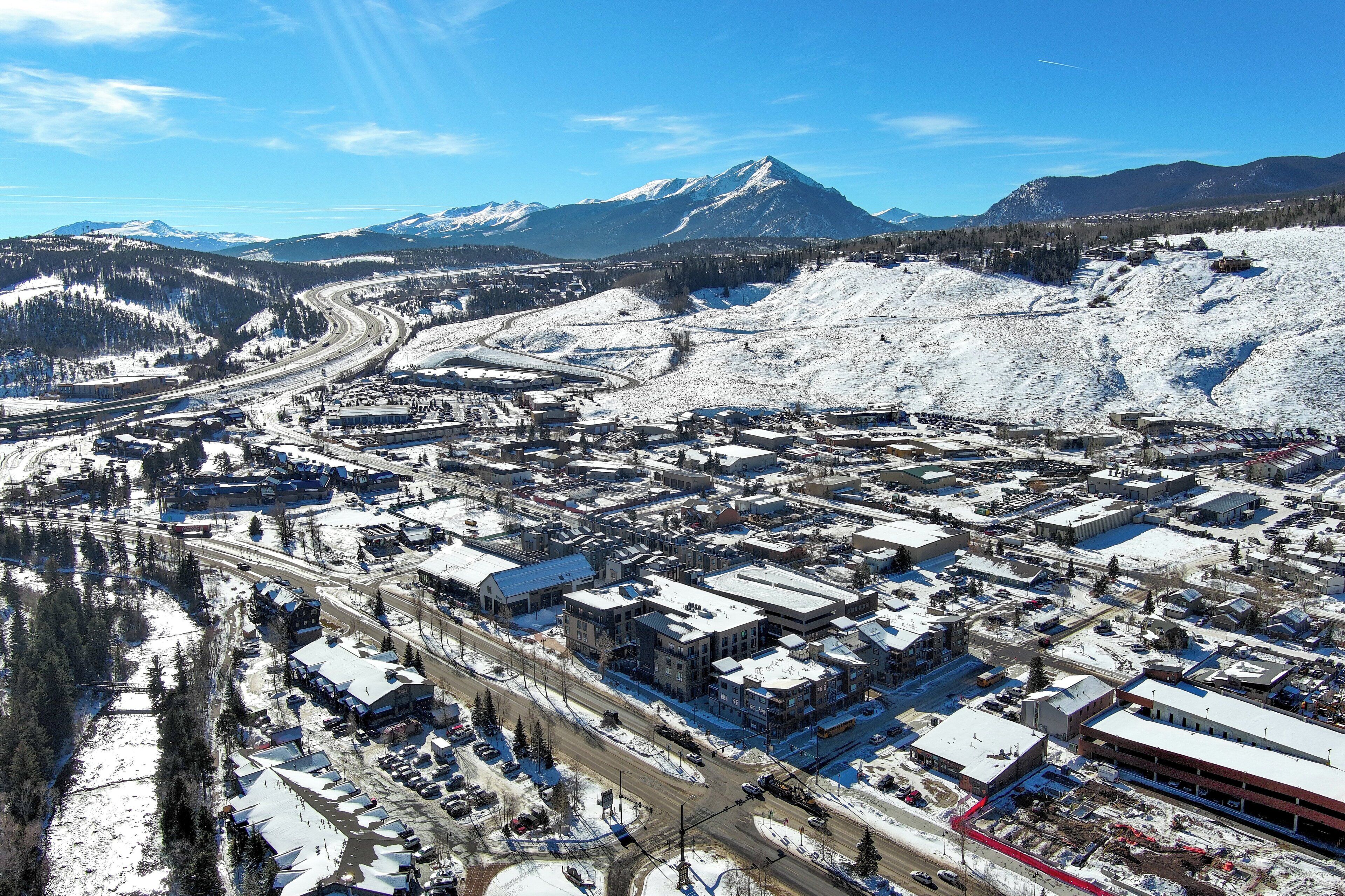 Une ville enneigée, avec des bâtiments et une montagne en arrière-plan.