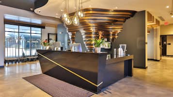 A modern reception desk with a unique curved design, a large window offering a view of the outside, and a clean, polished floor.