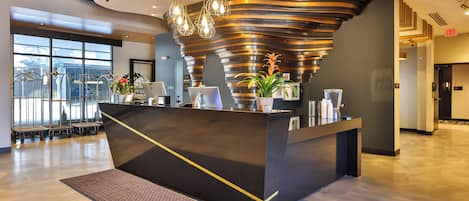 A modern reception desk with a unique curved design, a large window offering a view of the outside, and a clean, polished floor.