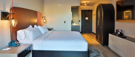 Una habitación de hotel moderna con una cama grande, una mesita de noche y un armario.