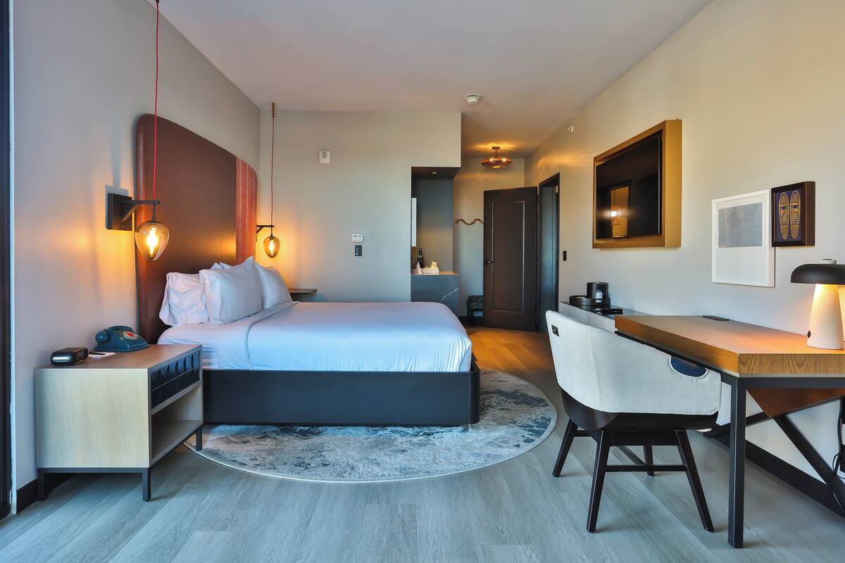 Una habitación de hotel moderna con cama, mesita de noche, escritorio y silla.