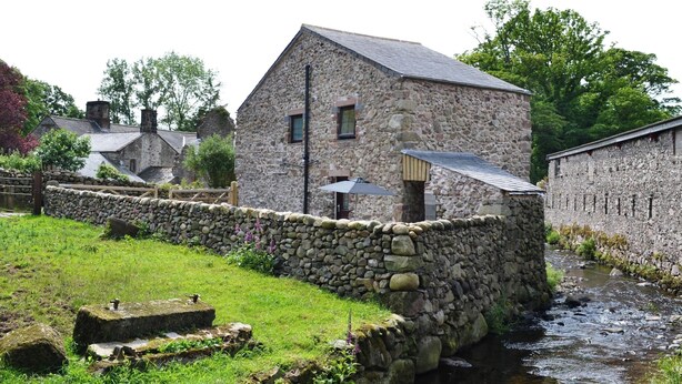A stone building with a sloped roof, a small window, and a door. - Character former shepherds cottage for couples or young families. (near Bootle)