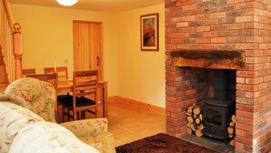 A cozy living room with a fireplace, wooden furniture, and a dining area. - Character former shepherds cottage for couples or young families. (near Bootle)