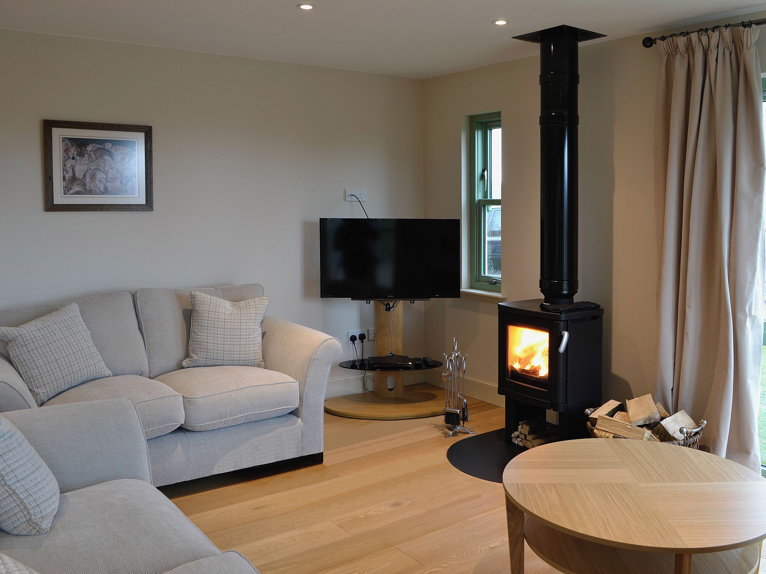 Una sala de estar con sofá, televisión, chimenea y ventana con cortinas.