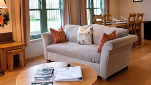 A living room with a sofa, a coffee table with magazines, a dining table with chairs, and large windows with curtains. - 3 bedroom accommodation in Linlithgow, near Edinburgh (Linlithgow, near Edinburgh)