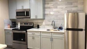 A modern kitchen with stainless steel appliances, white cabinetry, and a tiled backsplash. - Downtown Atlanta Condo with City View (Atlanta)
