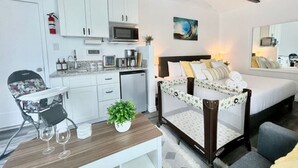 Ein Hotelzimmer mit Bett, Schreibtisch mit Stuhl, Mikrowelle, kleinem Kühlschrank und Deckenventilator.
