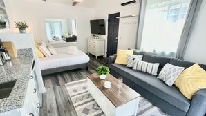 Ein modernes Wohnzimmer mit einer Couch, einem Couchtisch und einem Essbereich mit Küchenzeile.