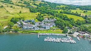 A lakeside property with a marina, large buildings, and surrounding green hills.