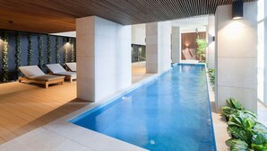 Un área interior de piscina moderna con sillones de descanso y una piscina larga.