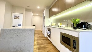Una cocina moderna con encimera de mármol, suelo de madera y electrodomésticos integrados.