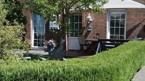 A brick building with a patio area, a table and chairs, and a potted plant. - Lüttje Fehn - Ostfriesische Idylle (Uplengen)