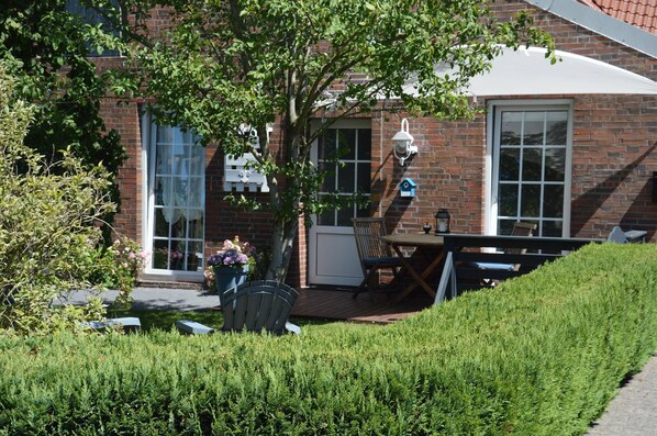 En murstensbygning med en patio, et bord, stole og en potteplante.