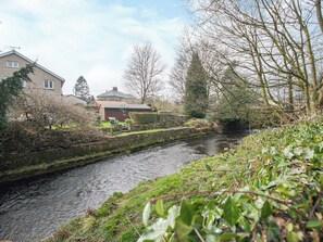 A narrow waterway flanked by stone walls and greenery, with buildings in the background.