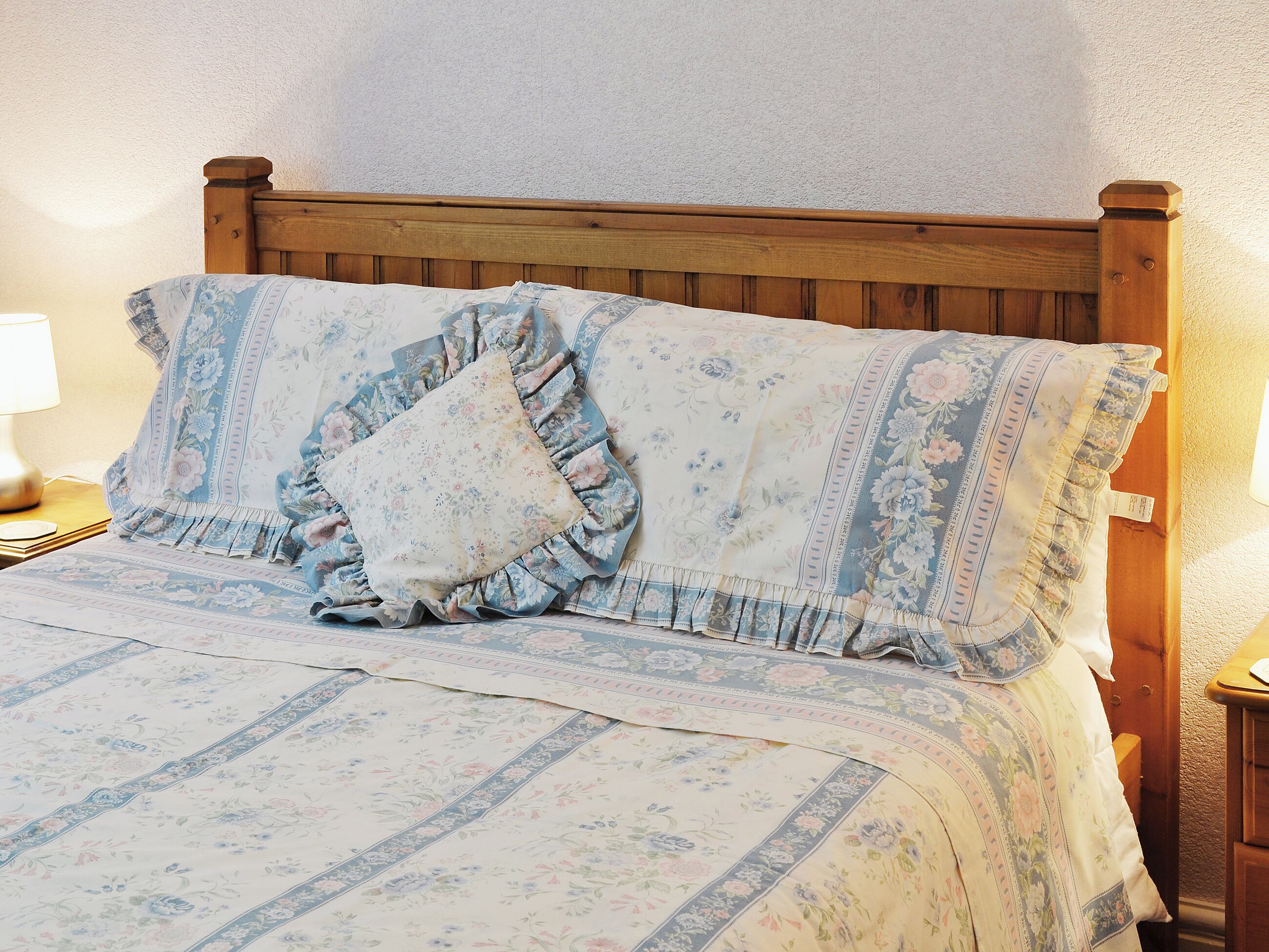 A bed with floral bedding and a wooden headboard.