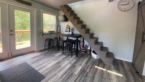 Eine Küche mit einer Holztreppe, einem Essbereich mit Barhocker und einer Uhr an der Wand.