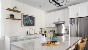 A modern kitchen with white cabinetry, a marble countertop, and a stainless steel refrigerator.
