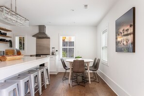 A modern kitchen with a central island, bar stools, and a dining table with chairs.