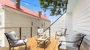A wooden deck with outdoor furniture, a staircase, and a brick chimney. - Private Pool! | Rooftop Patio | The Athena (Charleston)