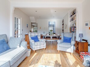 Un salon comprenant un coin repas, un plancher en bois et une bibliothèque.