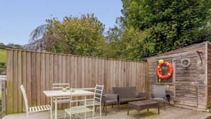 A wooden deck with outdoor furniture, including a table and chairs, and a small shed with a life ring on the wall. - 3 bedroom accommodation in Dartmouth (Dartmouth)