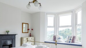 A bedroom with a bed, a dresser, a mirror, a window with a view, and a chandelier. - 3 bedroom accommodation in Dartmouth (Dartmouth)
