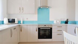 Una cucina moderna con mobili bianchi, un forno Bosch, un microonde e un tostapane.