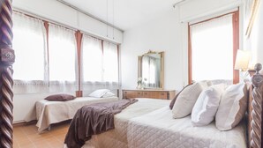 Una habitación de hotel con dos camas, un aparador de madera, un espejo y una ventana con cortinas.
