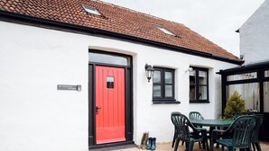 A red door with a small window, a table with chairs, and a sign reading 'st Oates Lodge'. - St David's Lodge - UK6738 (Lydstep, near Tenby)