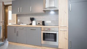 Een moderne keuken met grijze kastjes, een roestvrijstalen oven en een houten aanrecht.