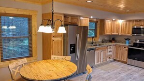 Una cocina moderna con armarios de madera, electrodomésticos de acero inoxidable y una mesa redonda de madera con sillas.