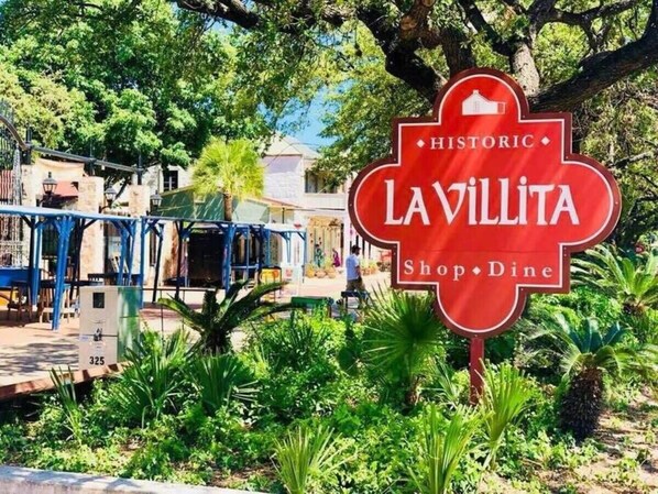 A historic La Villita Shop & Dine sign surrounded by lush greenery.