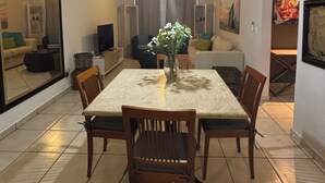 Un comedor con mesa y sillas, una lámpara colgante y un jarrón con flores.