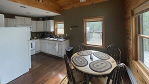 Ein Holzhütten-Interieur mit Küche, Essbereich und großen Fenstern.