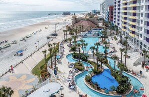 A resort with a beach, a pool area, and a large building with balconies. - Family-Friendly 2BR Dlx at Ocean Walk—Beach Access, Pools & Lazy River Included! (Daytona Beach)