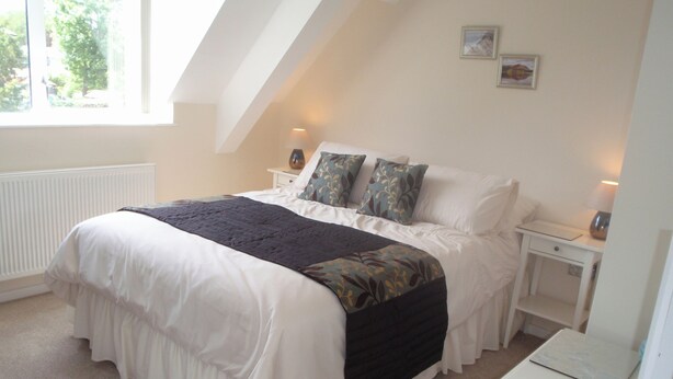 A bedroom with a large bed, a bedside table, a desk, and a radiator. - 2 bedroom accommodation in Staveley (Staveley)
