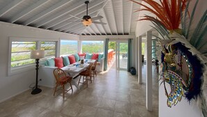 A spacious dining area with a high ceiling and large windows overlooking a lush landscape. - Fair Winds: Tropical Beach House, Stunning Ocean View, Pool, Steps to the Beach! (Farmer's Hill)