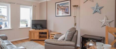 A living room with a sofa, a television, a fireplace, and decorative stars on the wall.