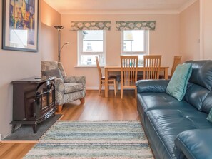 A living room with a sofa, a chair, a small table, a cabinet, and a rug.