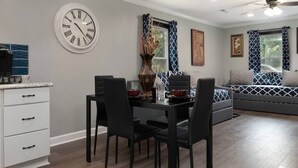 Een eetgedeelte met een ronde tafel, zwarte stoelen en een klok aan de muur.