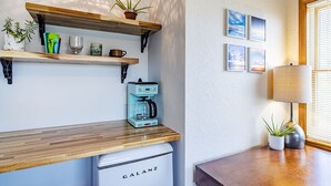A kitchen with wooden countertops, a coffee maker, a white refrigerator, and shelves with plants and kitchenware.